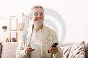 Senior man watching tv with remote control