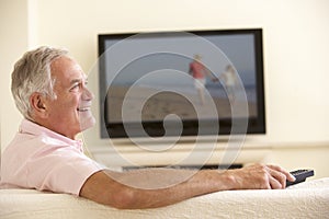 Senior Man Watching Widescreen TV At Home
