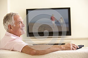 Senior Man Watching Widescreen TV At Home