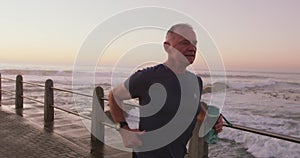 Senior man with water bottle running on the promenade