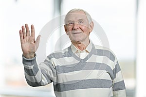 Senior man waving hand happily.