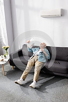 Senior man waving newspaper while suffering