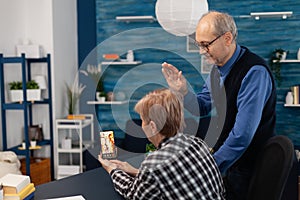 Senior man waving at smartphone camera