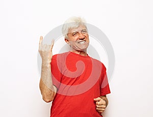 Senior man wearing casual red t-shirt standing over isolated white background shouting with crazy expression