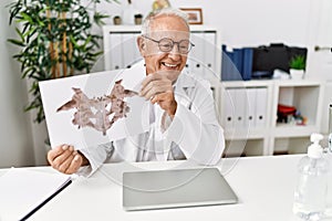 Senior man wearing doctor uniform doing rorscharch test at clinic