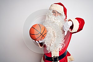 Senior man wearing Santa Claus costume holding basketball ball over isolated white background with angry face, negative sign