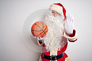 Senior man wearing Santa Claus costume holding basketball ball over isolated white background with open hand doing stop sign with