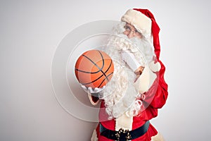 Senior man wearing Santa Claus costume holding basketball ball over isolated white background serious face thinking about