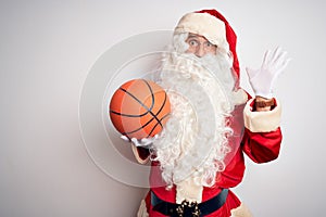 Senior man wearing Santa Claus costume holding basketball ball over isolated white background very happy and excited, winner