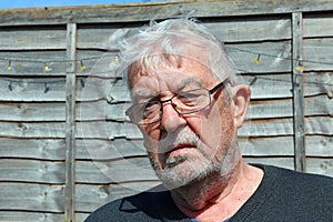Senior man wearing spectacles glaring towards camera