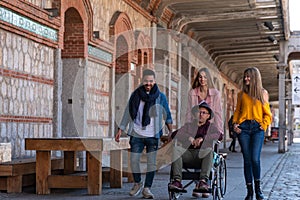Senior man in a wheelchair accompanied by happy youngsters