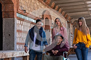 Senior man in a wheelchair accompanied by happy youngsters