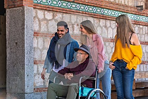 Senior man in a wheelchair accompanied by happy youngsters