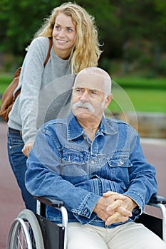 Senior man in wheelchair and daughter in park