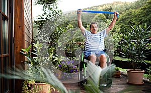 Senior man in wheelchair doing exercise on terrace.