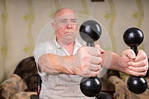 Senior Man in Wheelchair Lifting Dumbbells at Home