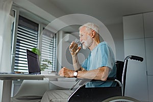 Senior man in a wheelchair shopping online on laptop. Elderly man using digital technologies, working on a notebook