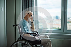 Senior man in a wheelchair spending time alone in his apartment.