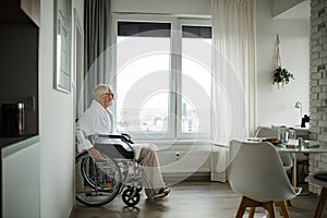 Senior man in a wheelchair spends time alone in his apartment.