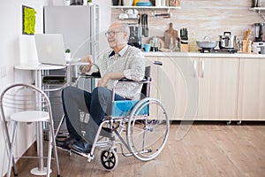 Senior man in wheelchair using laptop