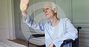 Senior man in wheelchair waving at home