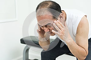 Senior man in white shirt having headache from stress and migraine while working out with white background.
