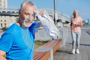 Senior man wiping sweat from the forehead with towel