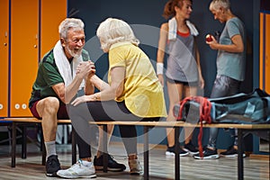 Senior man and woman arm wrestling and having fun in gym locker room