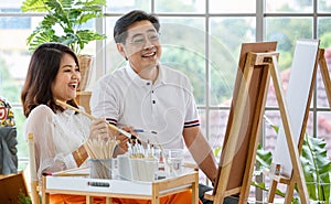 Senior man and woman couple, husband and wife, painting image together in home gallery with warm and happy circumstance. Idea for