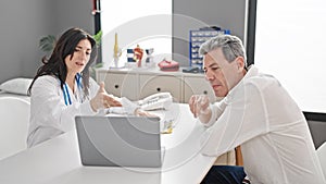 Senior man and woman doctor and patient having medical consultation looking laptop at clinic