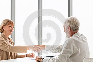 Senior man and woman handshake, Middle-aged lady shake hands with senior man, Smiling old mature saleswoman handshake client