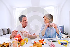 Senior man and woman having breakfast. Sunny morning.