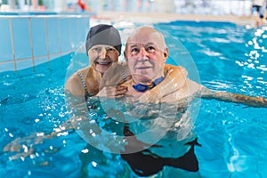 Senior man and woman hugging together in the swimming pool