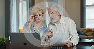 Senior man and woman paying bills and managing budget. Mature worried couple sitting and managing expenses at home.