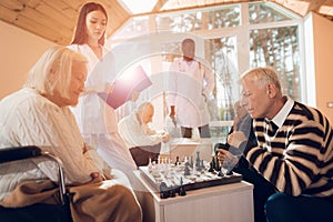 The senior man and woman play chess in the nursing home.