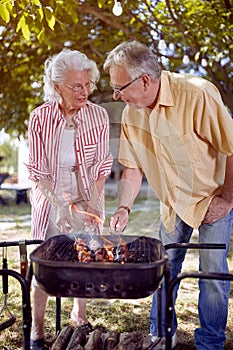 Senior man and woman preparing barbecue in garden together