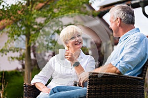 Senior man and woman sitting in front of house