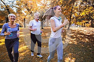 Senior man and woman and young female instructor workout on fresh air.