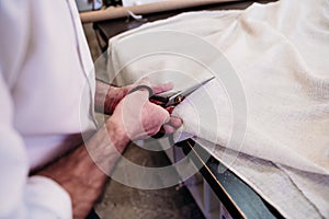 senior man working in atelier cutting curtains. Small business