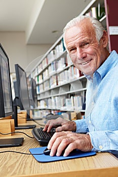 Senior man working on computer in library