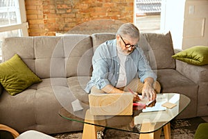 Senior man working with laptop at home - concept of home studying