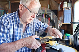 Senior Man Working On Model Radio Controlled Aieroplane In Shed At Home