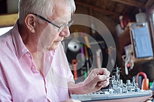 Senior Man Working On Model Ship In Shed At Home