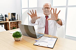 Senior man working at the office using computer laptop doing stop gesture with hands palms, angry and frustration expression