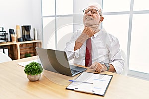 Senior man working at the office using computer laptop touching painful neck, sore throat for flu, clod and infection