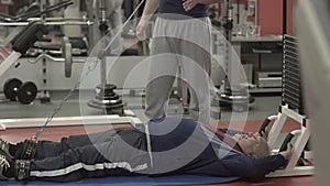 Senior man working out with a trainer in a gym