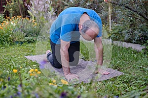 Senior man working out in yoga, pilates bend in Cat yoga Pose, Marjaryasana