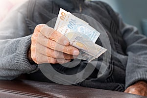 Senior man wrinkled hands holding Turkish Lira banknotes.Financial currency crisis concept