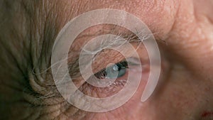 senior man with wrinkles looking and blinking close-up. Elderly male at optometrist for test for prescription lenses