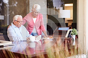 Senior Man Writing Memoirs In Book Sitting At Desk